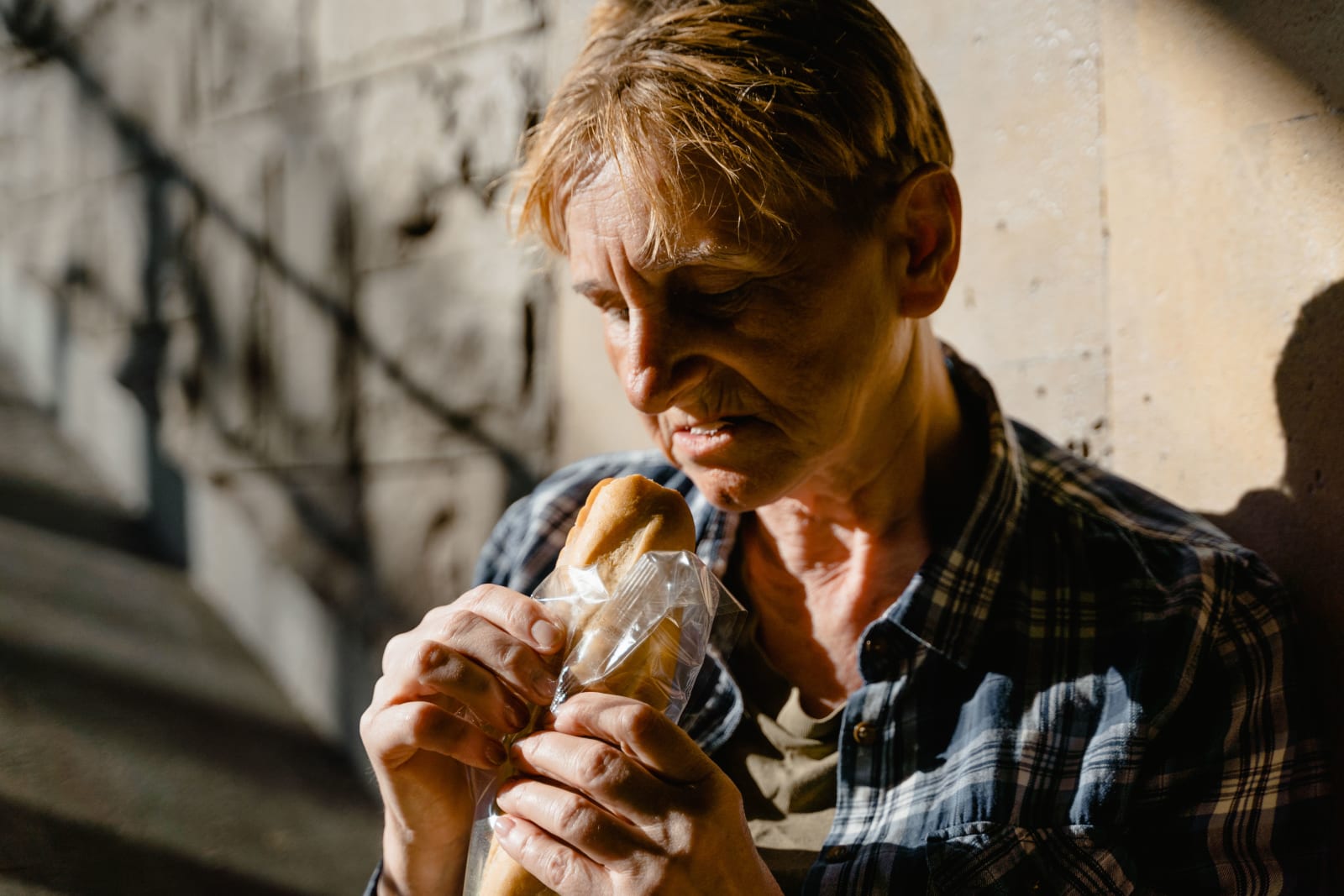 Homeless woman holding a bread roll (Representative Image Source: Pexels | MART PRODUCTION)