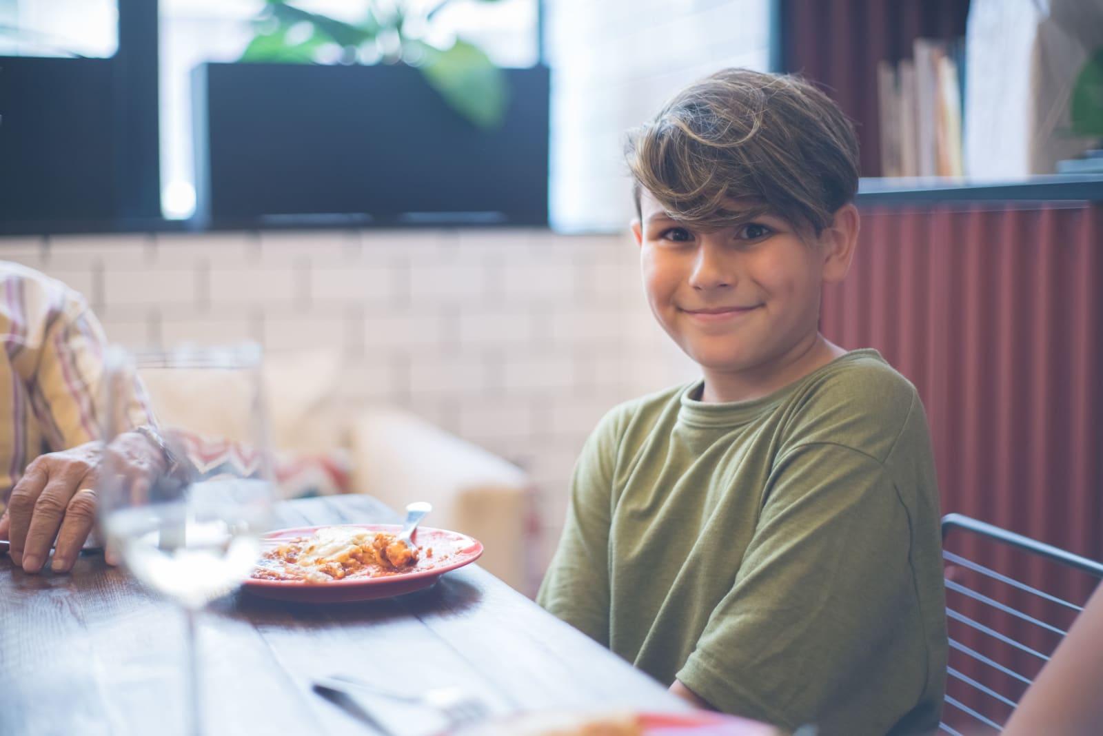 A little boy smiling at a restaurant. (Representative Image Source: Pexels| Kampus Production)