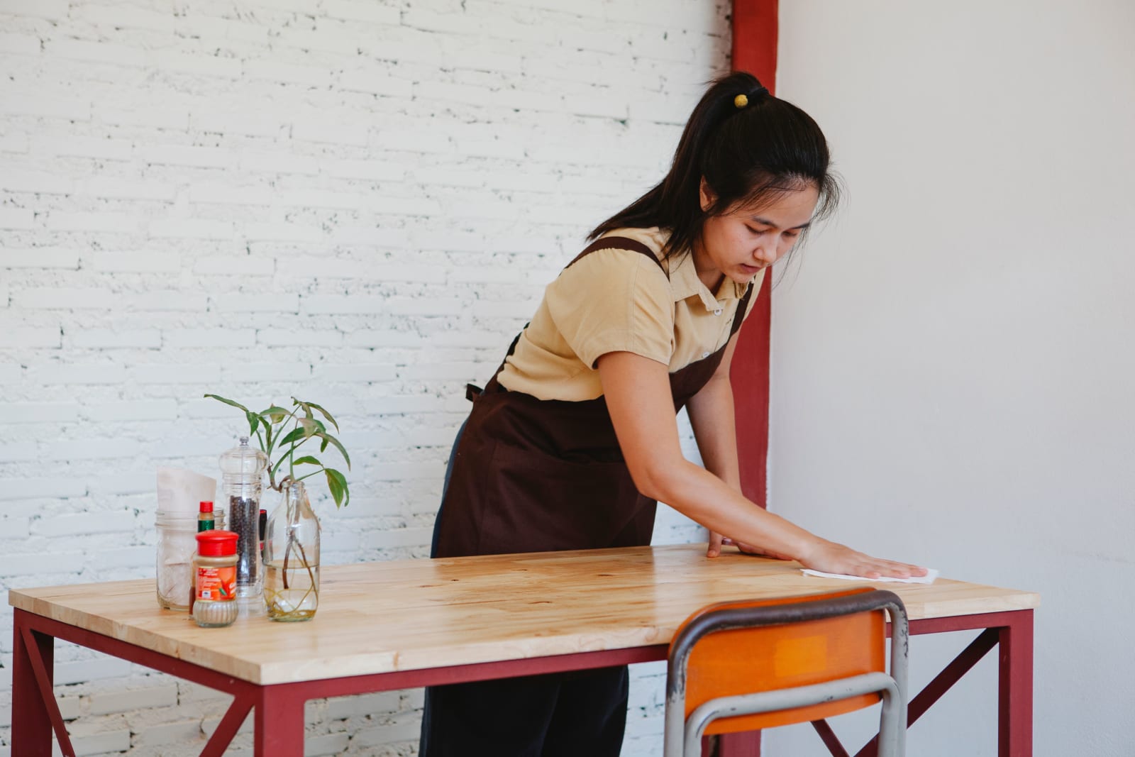 Waitress wiping a wooden table  (Representative Image Source: Pexels | Antonius Ferret)