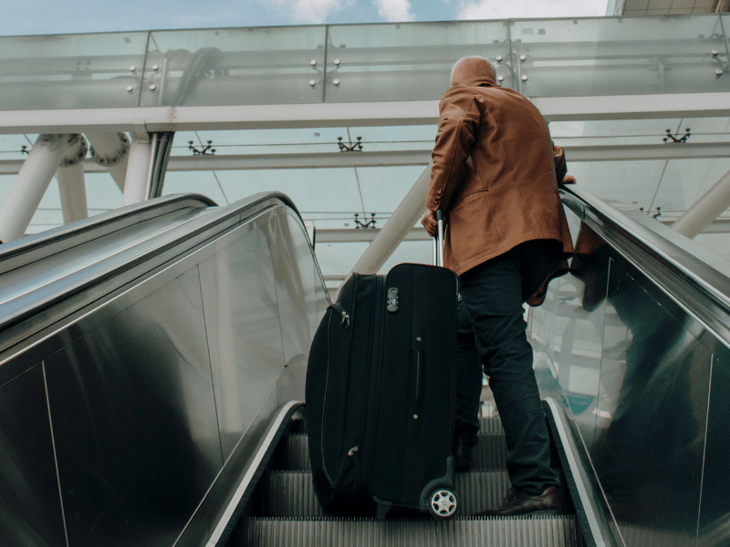 An old man rushing with a suitcase on an elevator.