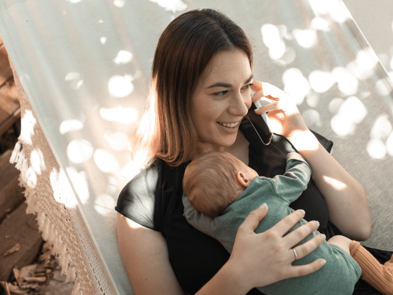 A new mother talking on phone while holding her baby.