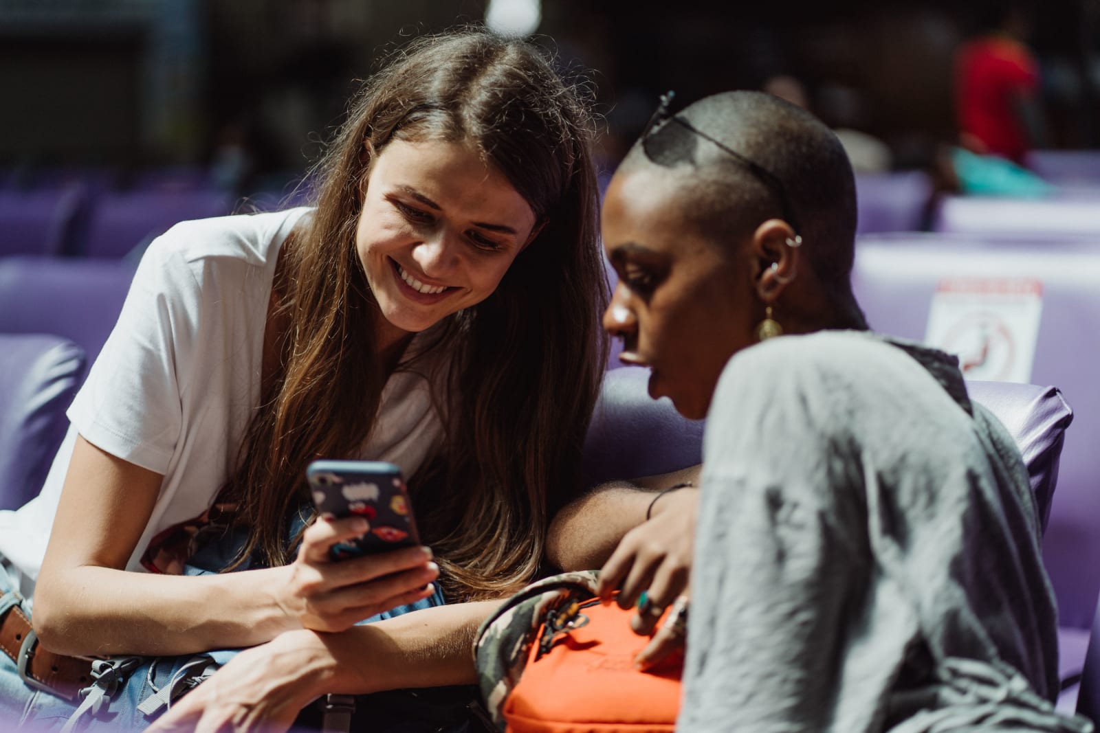 Two young women at the airport talking to each other.
