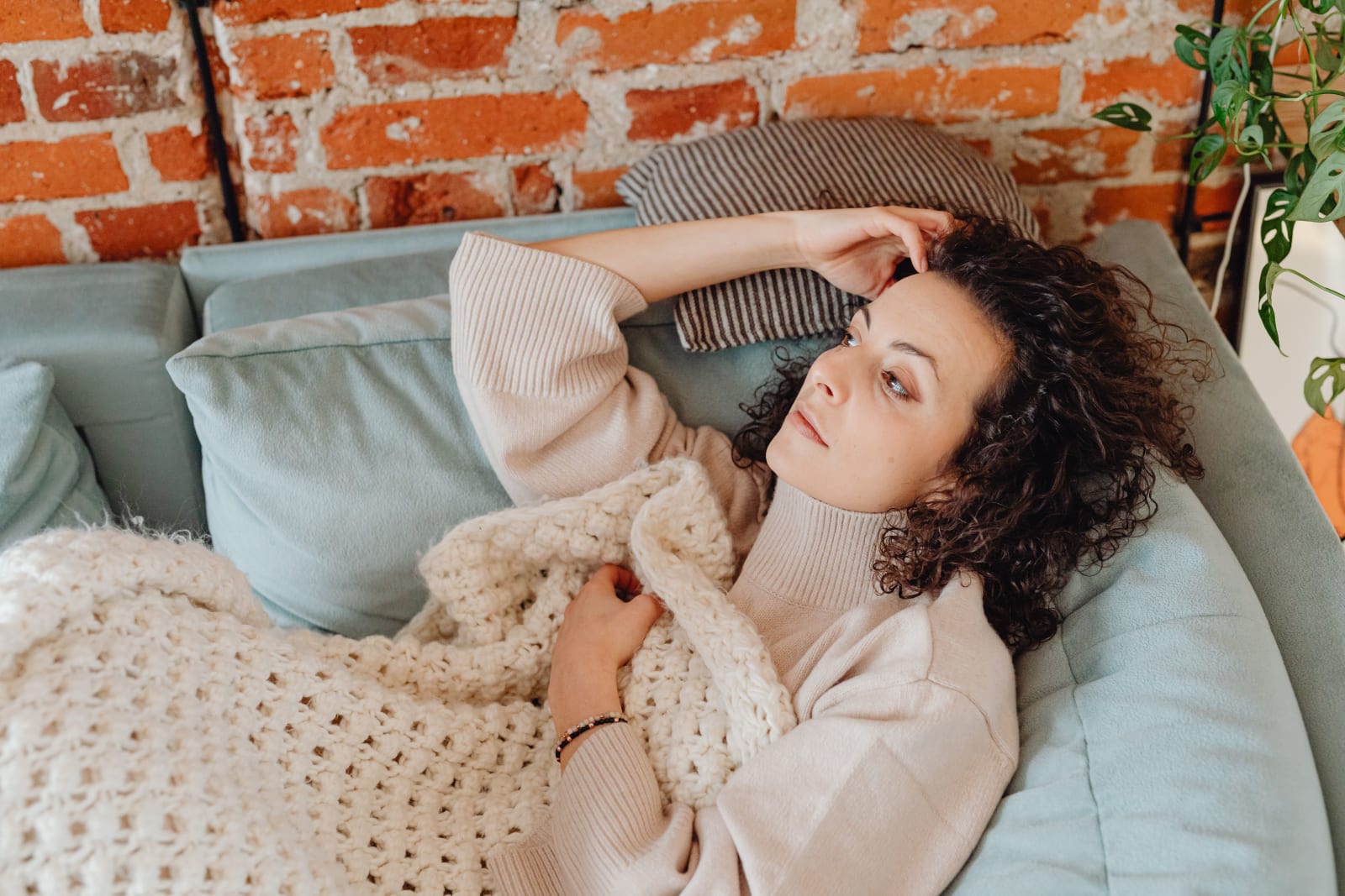 A woman lying in a blanket on a couch. (Representative Image Source: Pexels| Karola G)